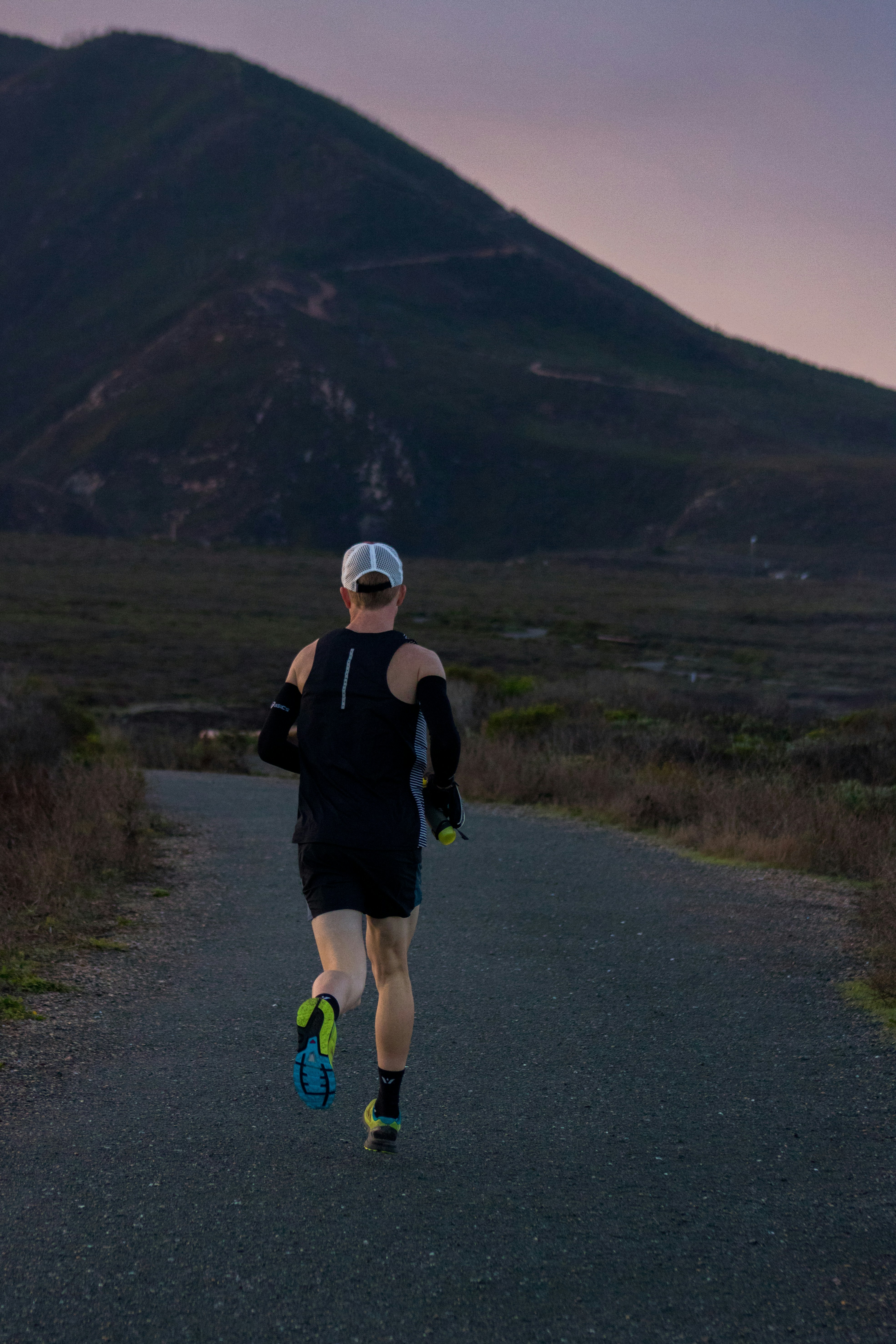 Coureur seul sur la route, montagne au crépuscule